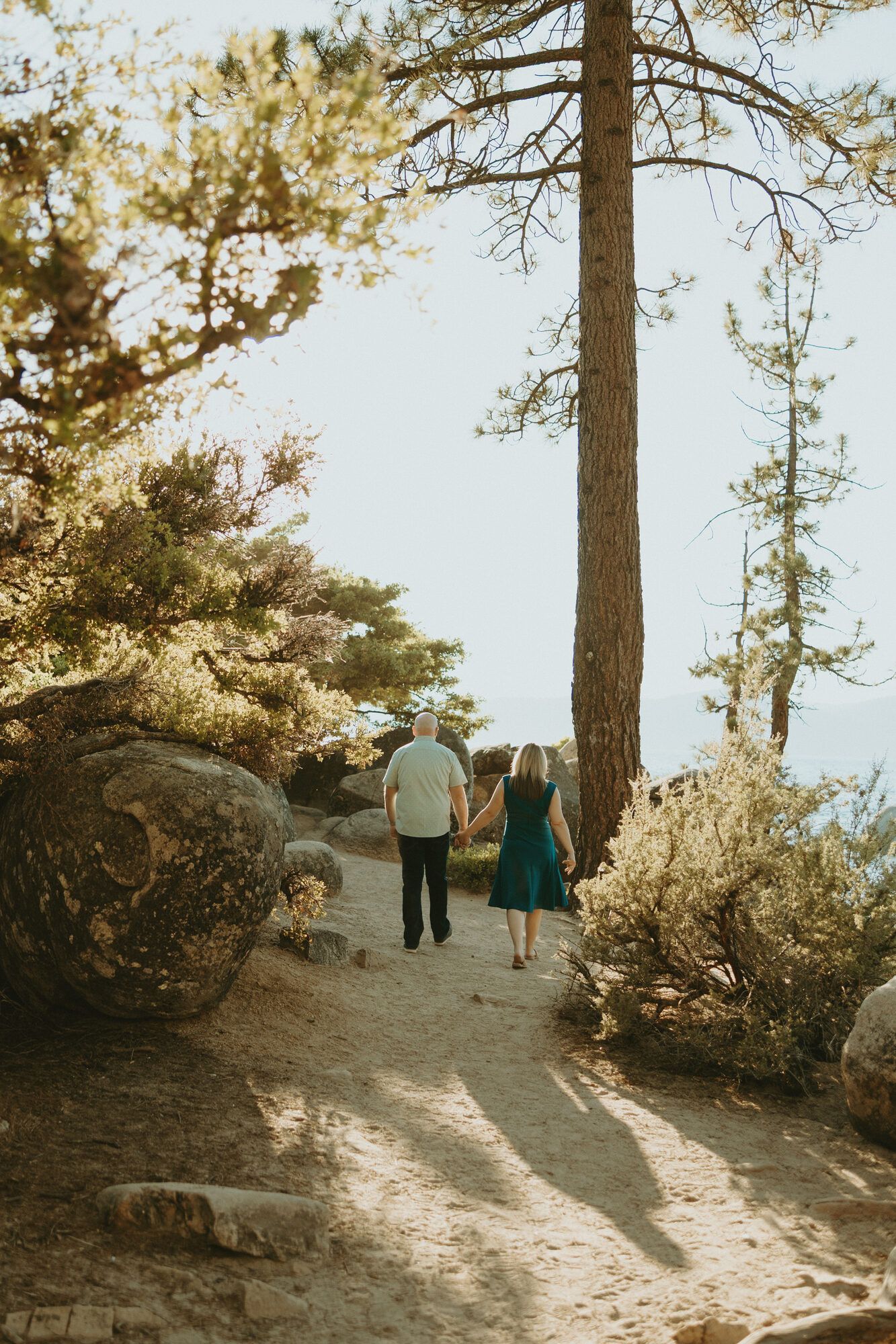 Strolling hand in hand beneath tall pines toward the lake