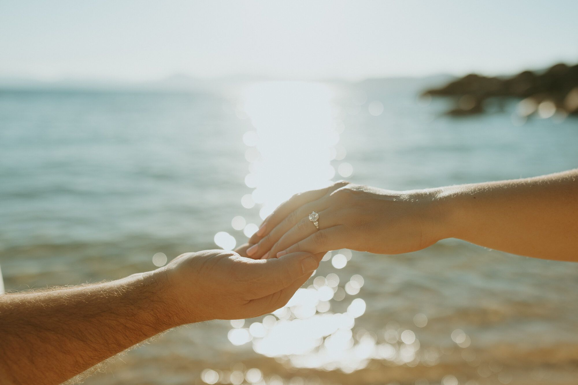 Nicole's engagement ring, hands clasped over the sparkling lake