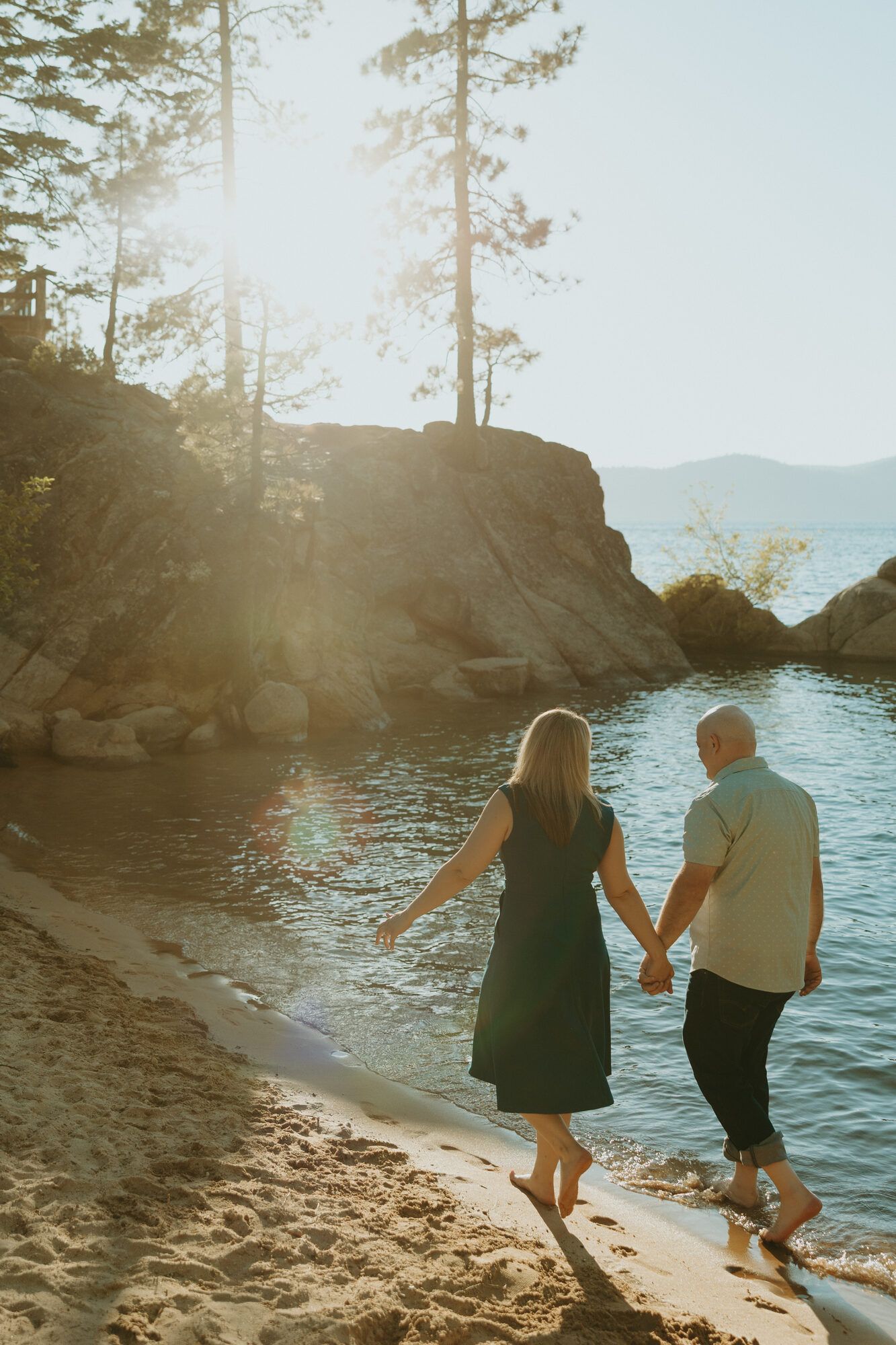 Nicole and Eric walking toward the sunlit cove, backlit by golden light